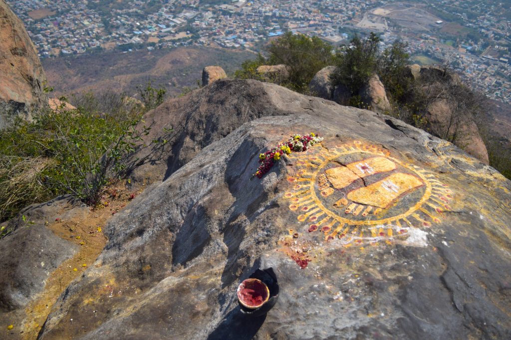 Feet symbol at the top view of Tiruvannamalai city and Arunacheshvara Temple from Arunachala hill with two travellers going down, Tamil Nadu India, panoramic view